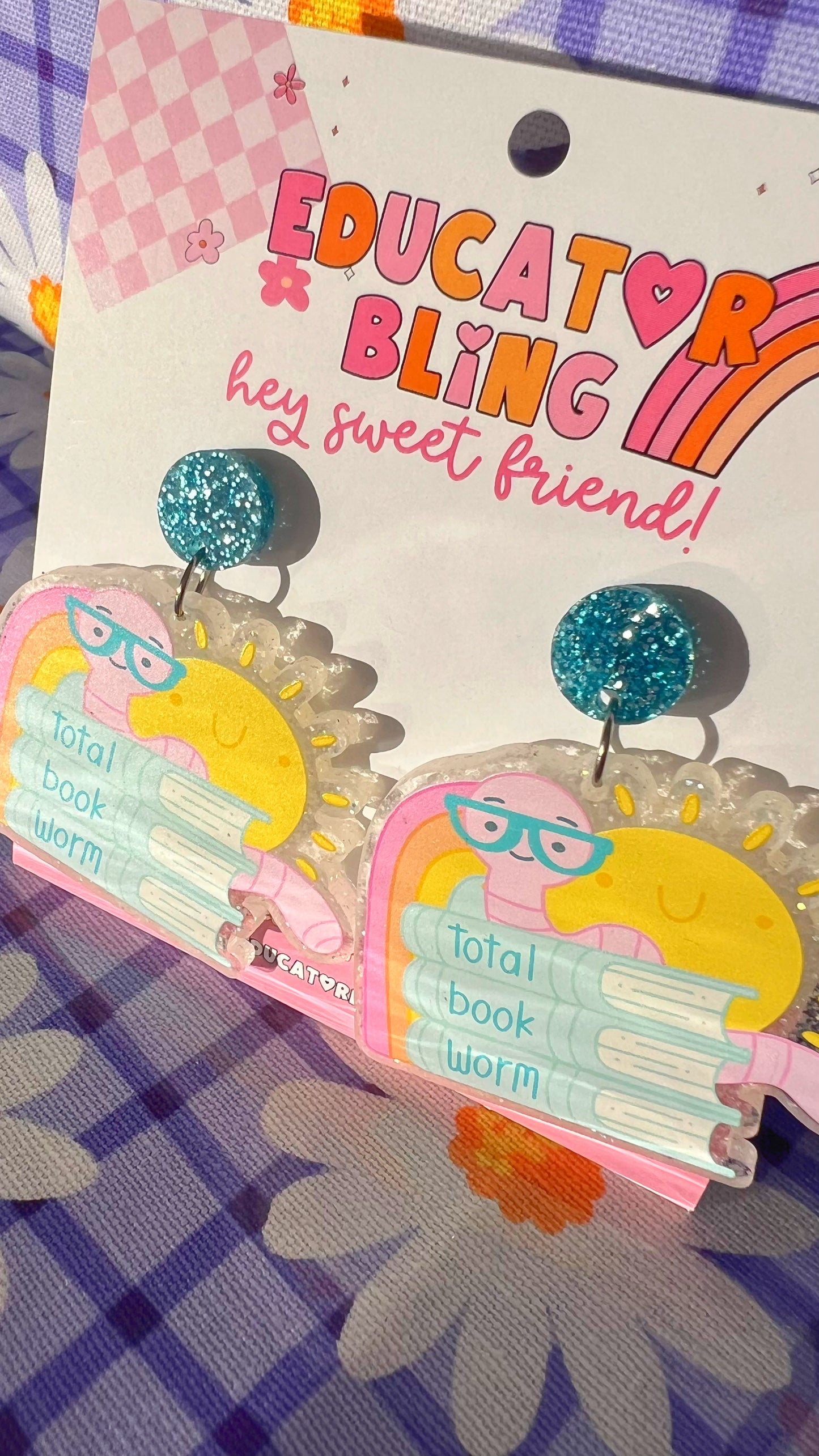 Close-up of the Total Book Worm teacher earrings showing the sun, bookworm and book-stack design