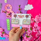 One More Chapter teacher earrings by Educator Bling – colourful acrylic dangle earrings with a pink flower stud and an open book reading 'One More Chapter', on a rainbow display card