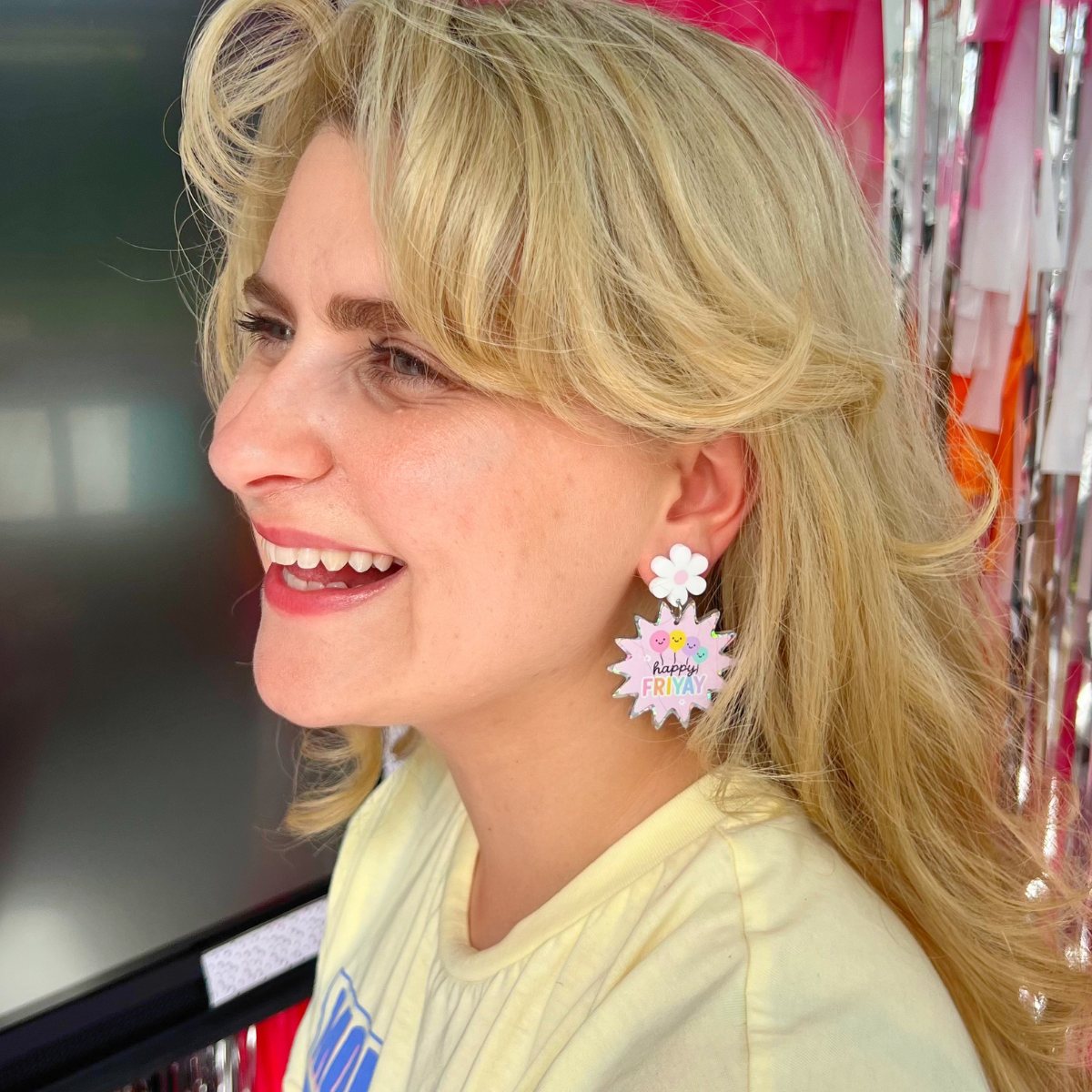 Teacher wearing Happy FriYAY rainbow sparkle acrylic dangle earrings in classroom – Educator Bling handmade accessory.